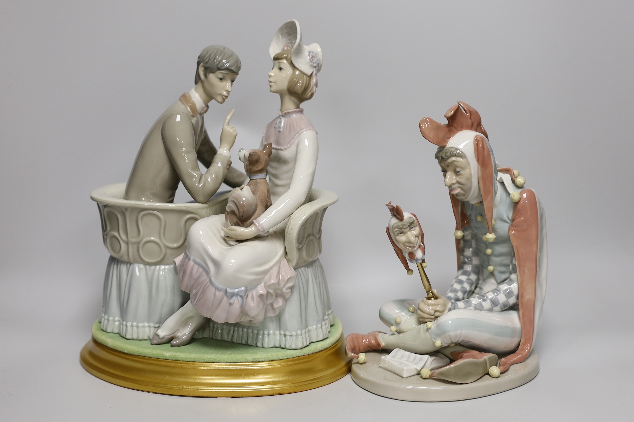 A large Lladro figure group of a couple and their dog on base together with a Lladro figure of a kneeling jester. Tallest 29cm